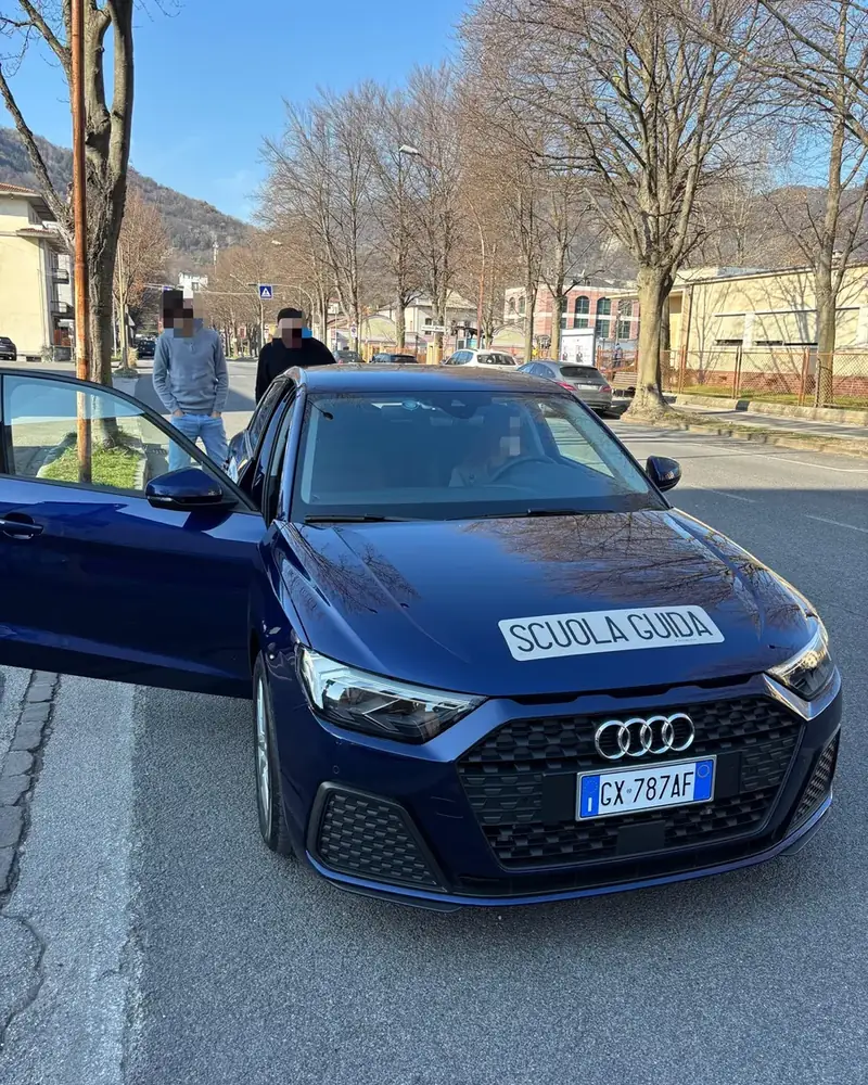 Istruttore e allievi con l'Audi A1 blu dell'Autoscuola De Zan prima di una guida